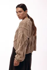 Sweater de tejido de punto grueso con diseño de rombos en relieve, cuello redondo y mangas largas amplias. Presenta una silueta relajada y holgada.