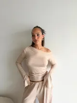 Blusa de lanilla color beige, con escote asimétrico tipo barco y mangas largas con terminación acampanada.