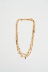 Collar multicapa de color dorado, compuesto por una cadena de eslabones gruesos y cadenas finas decoradas con dijes de estrellas y pequeñas perlas.
