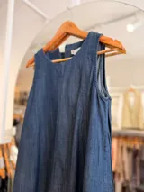 Vestido corto de denim azul sin mangas, con corte evasé amplio y fluido.