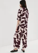 Pantalón largo de corte recto y tiro alto, con estampado abstracto en tonos bordó y crudo. Cuenta con cintura ajustable con elástico y un lazo incorporado para anudar.