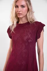 Vestido largo de crochet color crudo, con mangas cortas con volados y aberturas laterales, confeccionado en tejido calado de algodón con diseño ornamentado.