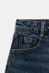 Falda pantalón de denim azul con diseño de cinco bolsillos, cierre frontal con cremallera y botón, y bajo deshilachado sin costuras.