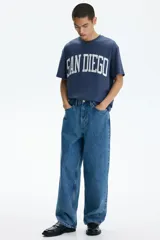 Remera de algodón de peso medio, color azul, con cuello redondo ribeteado, hombros caídos, bajo recto y corte holgado. Presenta un estampado frontal con la inscripción "SAN DIEGO" en blanco con efecto desgastado.