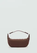 Bolso de hombro pequeño en color marrón, con diseño de media luna, asa corta y detalle de tachuelas metálicas decorativas a lo largo de la base. Cuenta con cierre de cremallera superior.