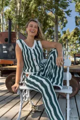 Pantalón tejido de corte recto y tiro alto, con diseño de rayas verticales onduladas en colores beige y negro. Presenta una cintura elástica con cordón ajustable.