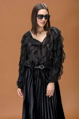 Camisa negra de tela semitransparente con volados frontales y en las mangas, escote en V y cierre frontal con botones.