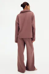 Buzo en tejido liviano color malva con cuello camisero, tapeta de botones, hombros caídos y puños acanalados.