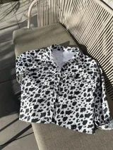 Camisa de denim con estampado de manchas de vaca, corte recto y cierre frontal con botones.