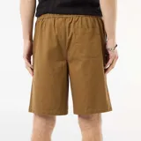 Bermuda estilo chino color marrón, de corte recto y holgado, con bolsillos laterales y trabillas para cinturón.