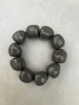 Pulsera elástica compuesta por cuentas de resina de gran tamaño con acabado brillante, disponible en combinaciones de colores gris, naranja y verde.
