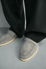 Mocasín casual de hombre, color marrón oscuro (bordó), fabricado en piel con acabado serraje (gamuza). Presenta un detalle de antifaz en el empeine y suela a contraste de color beige claro.