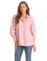 Camisa blanca de la marca Liv Los Ángeles, con cuello con solapa y cierre frontal de botones. Presenta mangas largas con detalles calados y puños anchos con botones.