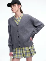 Cardigan gris de punto con textura tipo Shetland, escote en V, cierre frontal con botones y diseño de hombros caídos.