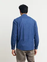 Camisa de cuello mao y manga larga, confeccionada en una mezcla de lino y algodón. Presenta un diseño de corte recto con botones en tono natural y un bolsillo pequeño en el pecho.