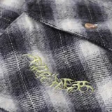 Camisa a cuadros blanco y negro con dos bolsillos frontales con botón y logo bordado en verde.