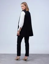 Chaleco largo tejido color blanco de la marca Sioni, con cuello solapa, doble botonadura dorada en el frente y bolsillos aplicados.