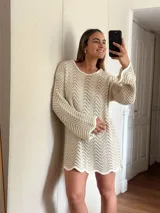 Vestido corto de tejido calado con patrón de ondas, confeccionado en algodón y lurex. Presenta mangas largas, cuello redondo y diseño holgado.