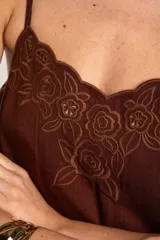 Musculosa blanca de viscosa con tirantes finos, escote en V y detalle de bordado floral con recortes en el borde superior.