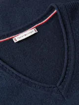 Sweater Tommy Hilfiger de cuello en V, confeccionado en pura lana. Presenta un diseño de corte regular con terminaciones enrolladas en cuello, puños y bajo, y el logo de la marca bordado en el pecho.