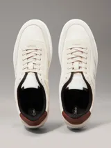 Zapatillas de corte bajo Calvin Klein Jeans en color beige, confeccionadas en una combinación de ante y piel nobuck. Presentan un diseño minimalista con suela cupsole blanca, detalle de trabilla trasera en color marrón y forro interior en contraste negro. Incluye el logo de la marca grabado en el lateral y en la mediasuela.