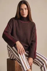 Polera de punto con calce oversize, color marrón oscuro con detalles en bordó en el cuello y franjas laterales en las mangas. Presenta cuello alto y puños acanalados.