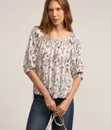 Blusa blanca con estampado floral negro, escote hombro a hombro y mangas 3/4 abullonadas.
