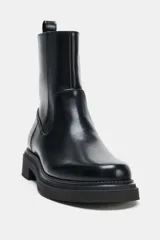 Botín de caña media con acabado liso, cierre lateral y tirador trasero. Presenta suela de plataforma y punta redonda.