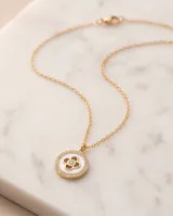 Collar de acero con baño de oro, compuesto por una cadena fina y un dije circular con incrustaciones de nácar y circonias.