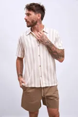 Camisa de manga corta color beige con rayas verticales marrones, cuello tipo cubano y bolsillo en el pecho.