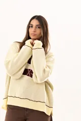 Buzo tejido de punto en color manteca, con diseño frontal de dos sardinas en color bordó. Presenta detalles bordados a mano en los bordes de las figuras y terminaciones con galón picot en cuello, puños y ruedo. Posee un corte holgado y aberturas laterales en el bajo.