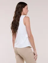 Chaleco blanco sin mangas de estilo smart-casual, con escote en V y costuras verticales de entalle. Cuenta con bolsillos o solapas simuladas a los lados de la cintura decorados con un botón metálico dorado y un largo a la cadera.