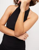 Pulsera dorada con forma plana, bañada en oro de 18k, con cierre de mosquetón.