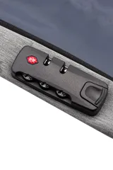 Mochila urbana con carcasa frontal rígida de color negro con diseño geométrico y logo 'VM' en blanco. Los laterales y la espalda son de tela gris jaspeada. Incluye un candado de combinación de tres dígitos integrado en el lateral.