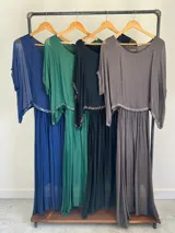 Vestido largo de seda italiana en color gris oscuro, con falda larga lisa, forro y cintura elastizada. Posee una sobrecapa con detalles de paillettes en los bordes de las mangas y la cintura.