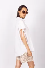 Camisa sin mangas color verde esmeralda, con cuello clásico, cierre frontal con botones y tiras regulables en los hombros.