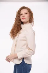 Camisa color blanco con cuello alto con volados y cierre frontal con botones ocultos.