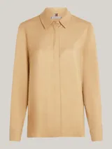 Camisa color beige de viscosa, de corte amplio, con cuello inglés, cierre frontal con botones y logo metálico de Tommy Hilfiger en la manga.