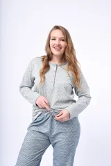 Pijama de dos piezas compuesto por una remera de manga larga con cuello redondo y cartera de botones, y un pantalón largo de corte recto. Ambas prendas presentan un estampado geométrico sutil en tonos gris y azul.