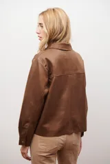 Chaqueta color camel con cuello camisero, cierre frontal con botones dorados, dos bolsillos de parche en el pecho y costuras decorativas en contraste.