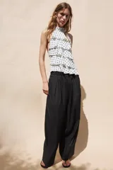 Top halter blanco con estampado de lunares negros y diseño de múltiples volantes en capas.