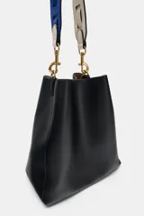 Bolso de hombro formato saca de color negro, con cierre mediante clip metálico y un compartimento interior extraíble con cremallera. Incluye un asa de hombro con diseño estampado y detalles metálicos dorados.