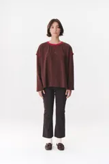 Remera de manga larga con corte oversized, color azul marino con cuello redondo en contraste color marrón. Presenta costuras decorativas a contratono hechas a mano en la zona de los hombros y logo bordado en el centro del pecho.