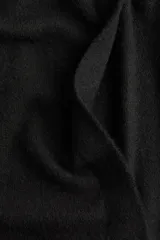 Saco largo negro de punto fino con lana, hombros caídos y ribete acanalado en nuca, puños y bajo. Sin cierre.