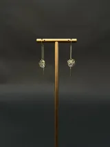 Aros colgantes de cadena fina con dije de esfera calada en forma de rosa que encierra una circonia central brillante.