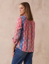 Blusa de gasa estampada multicolor, marca Ruby Rd. Tiene cuello a la base, escote en V, abertura central con botones y plisados en la parte delantera. Las mangas son 3/4 y tienen un largo regulable con presilla y botón.