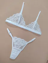 Conjunto de lencería de encaje blanco, compuesto por un soutiene triangular sin relleno con tirantes regulables y una bombacha colaless ajustable con detalles de encaje.