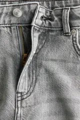 Jean de cinco bolsillos en denim de algodón rígido, de corte holgado estilo baggy, con piernas rectas y tiro alto. Presenta efecto deslavado y cierre con botón y cremallera.