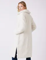 Tapado largo color blanco de tejido bouclé, marca Bcbg Maxazria. Cuenta con cuello de solapa amplia, cierre frontal con botones a presión internos, bolsillos funcionales y tajos laterales en el bajo. Forro interno a tono.