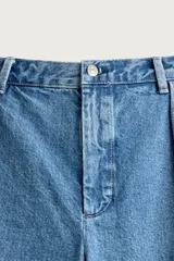 Bermuda de denim con corte relaxed fit, tiro medio y pierna recta. Presenta pliegues frontales dobles, bolsillos laterales y bolsillos traseros de doble vivo. Confeccionada en tejido rígido con efecto lavado, cierre frontal con cremallera y botón.